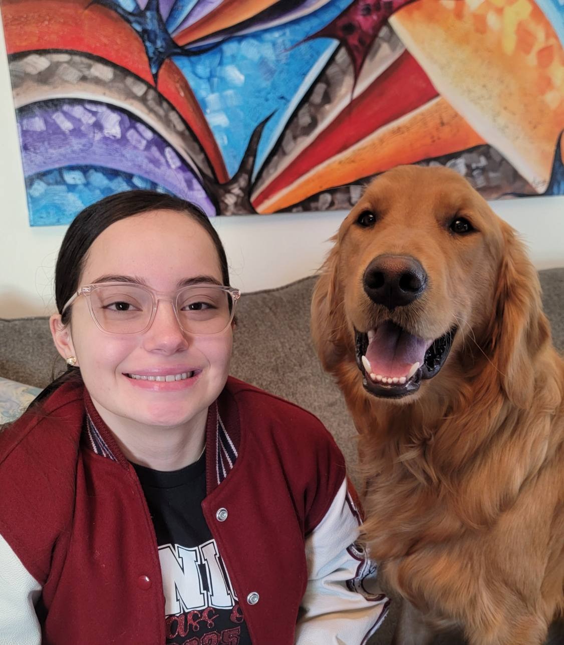 Woman and golden retriever smiling indoors.
